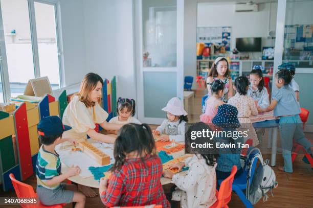2人のアジア系中国人モンテッソーリ幼稚園教諭が教室のおもちゃのブロックで生徒を見せる - surrounding ストックフォトと画像