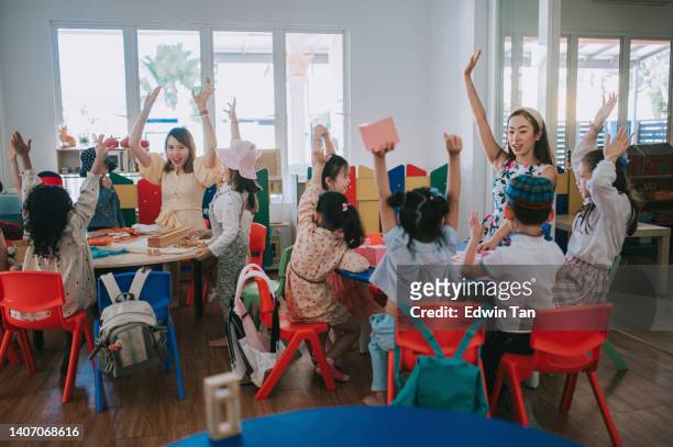 asiatischer montessori-vorschulschüler hob in der klasse die hände und beantwortete die frage - montessori education stock-fotos und bilder