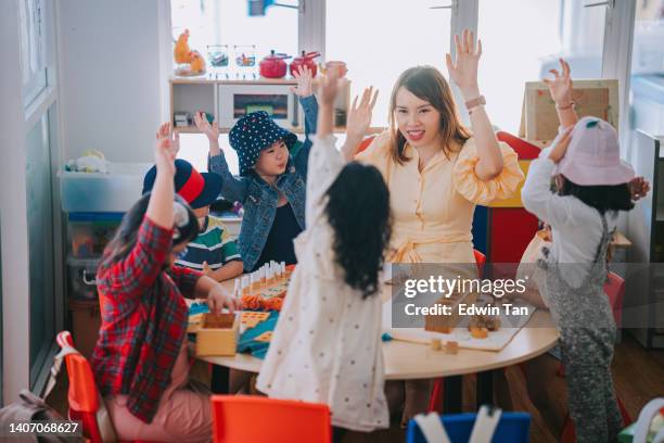 asian montessori preschool student raised hands in the class answering question - surrounding support stock pictures, royalty-free photos & images