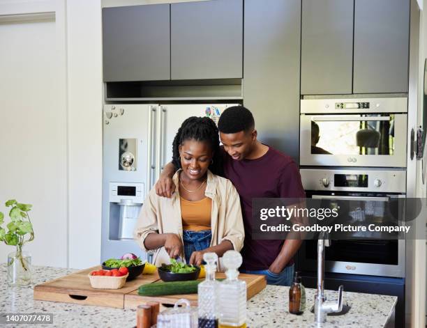 smiling young couple preparing a healthy meal in their kitchen - chopping stock pictures, royalty-free photos & images