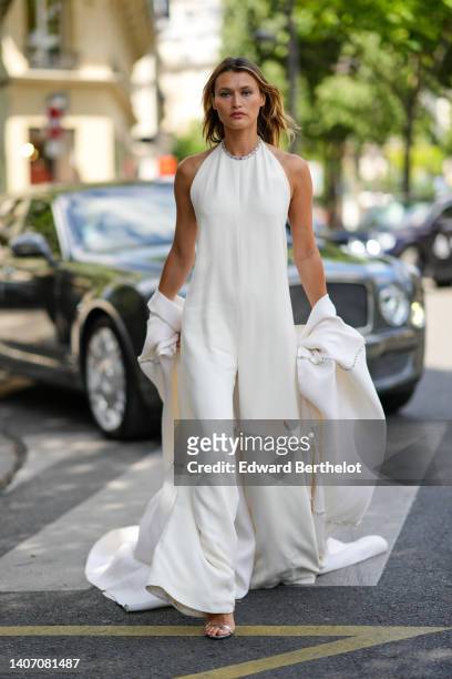 Chloe Lecareux wears a white latte halter neck with embroidered rhinestones / sleeveless / flowing flared jumpsuit, a white latte silk long kimono,...