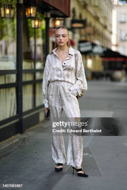 Anouchka Gauthier wears gold and pearls earrings, a beige with black print pattern silk shirt, matching beige with black print pattern silk large...