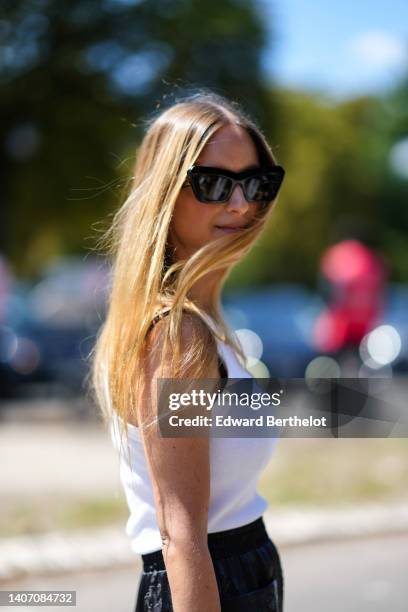 Charlotte Groeneveld wears black sunglasses from Loewe, a white tank-top, a gold chain necklace, a gold Juste Un Clou bracelet from Cartier, gold...