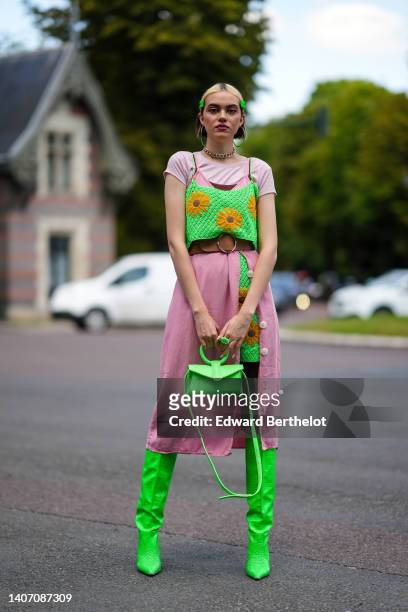 Rose BLM wears gold and green earrings, a gold large chain necklace, neon green hair clips, a pale pink ribbed short sleeves t-shirt, a neon green...