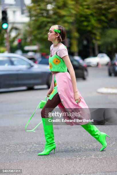 Rose BLM wears gold and green earrings, a gold large chain necklace, neon green hair clips, a pale pink ribbed short sleeves t-shirt, a neon green...