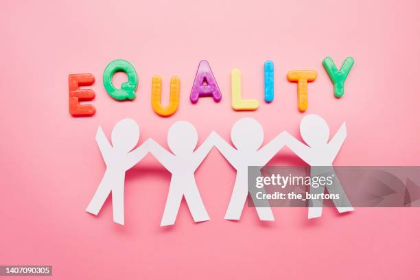 high angle view of paper people with arms raised and colorful letters of the word equality on pink background - respect word stock pictures, royalty-free photos & images