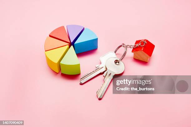 high angle view of pie chart made of colorful building blocks and keys with a small house on pink background - cake sale stock-fotos und bilder
