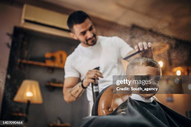 cute little boy at the barber shop getting his hairut - kapsalon stockfoto's en -beelden