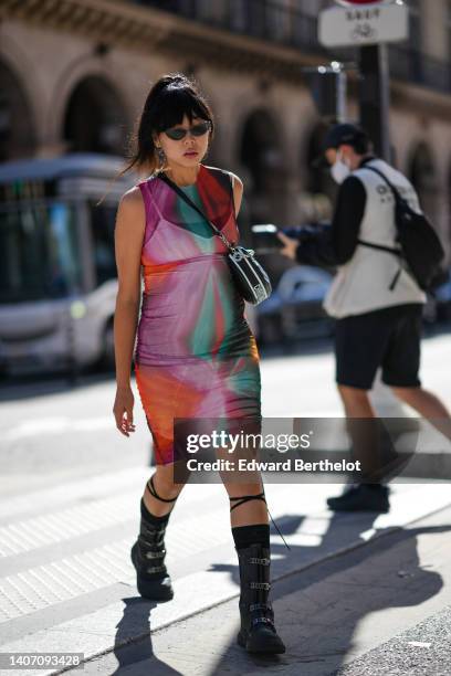 Susanna Lau wears black cat eyes sunglasses, a red / purple / green print pattern sleeveless / short tube dress, a black shiny leather and white...