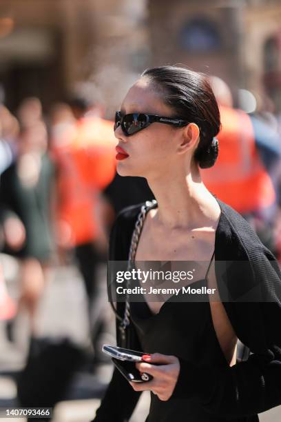 Guest seen wearing black sunglasses from Balenciaga, a black knit bolero/cardigan and a black sling dress, outside the Schiaparelli show, during...