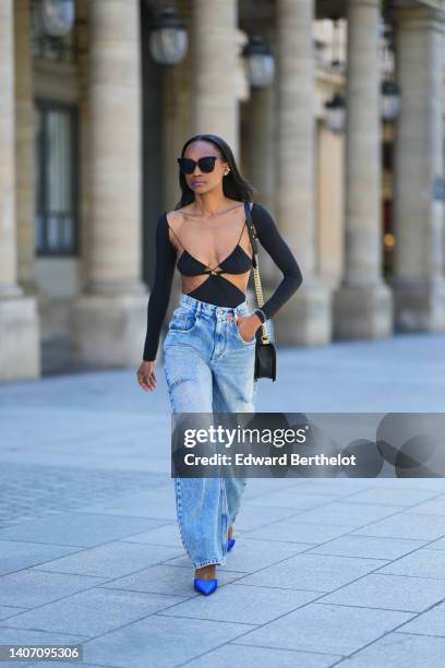 Emilie Joseph wears black sunglasses, a black shiny grained leather Boy shoulder bag from Chanel, a black Cut out dress worn as a dress from Amazuin...