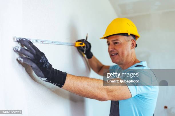 male carpenter measuring the kitchen wall with measuring tape - 50 meter stock pictures, royalty-free photos & images