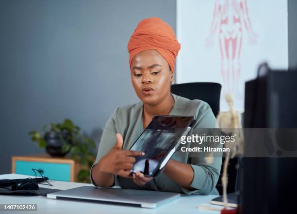 doctor showing an xray in a consultation. serious orthopaedic surgeon using a digital tablet to explain an operation in a hospital clinic office. african medical professional using modern technology - office holding sign stockfoto's en -beelden