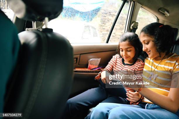 two girls playing/ watching on digital tablet - travelgame stock pictures, royalty-free photos & images