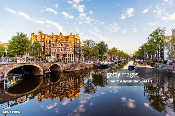 traditional dutch houses reflecting in the canal in jordaan neighbourhood, amsterdam, netherlands - amsterdam canal fotografías e imágenes de stock