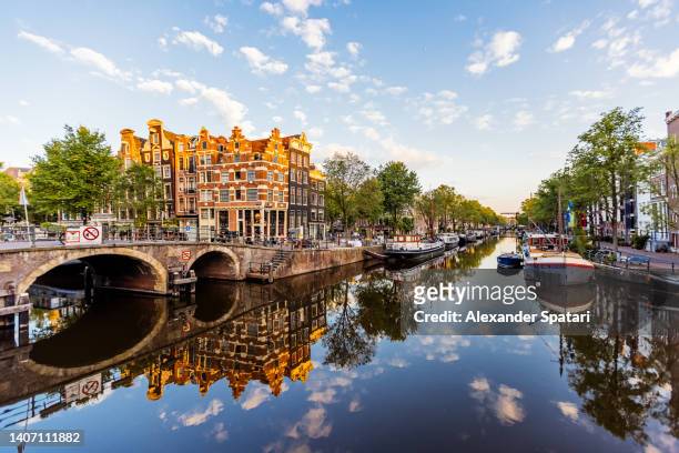 traditional dutch houses reflecting in the canal in jordaan neighbourhood, amsterdam, netherlands - amsterdam skyline stockfoto's en -beelden