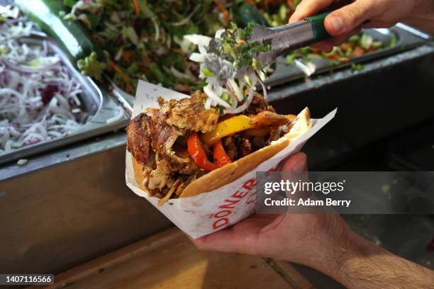 An employee prepares a customer's order at Mustafas Gemüse Kebap on July 06, 2022 in Berlin, Germany. The döner kebab, a fast food sandwich made of...