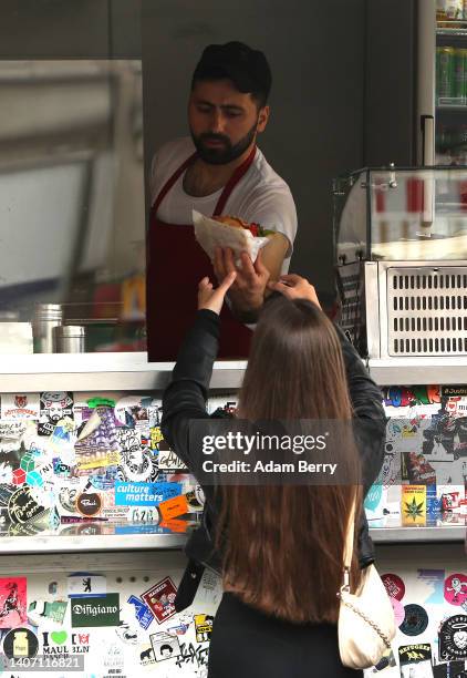 Customer receives her döner kebap at Mustafas Gemüse Kebap on July 06, 2022 in Berlin, Germany. The döner kebab, a fast food sandwich made of...