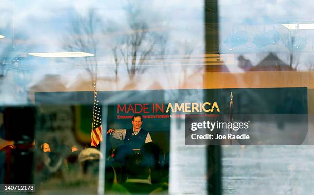 Republican presidential candidate, former U.S. Sen. Rick Santorum is seen through a window as he speaks during a campaign rally at the Dayton...