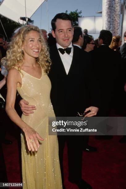 American actress Sarah Jessica Parker, wearing a yellow dress with gold thread detail, and her husband, American actor Matthew Broderick, wearing a...