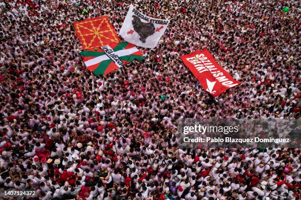 Giant Ikurrina flag of the Basque Country is displayed next to Basque political banners as revellers enjoy the atmosphere during the opening day or...