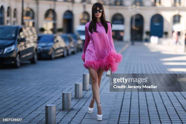 Sabina Jakubowicz seen wearing black mirrored sunglasses, a pink long sleeves short dress with feather borders from Alexandre Vauthier, a white...