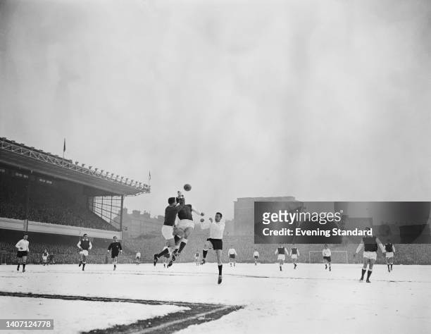 Northern Irish footballer Jack McClelland , Arsenal goalkeeper, British footballer Laurie Brown , Arsenal defender, look to clear the ball from...