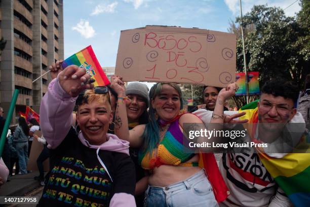 Demonstrators pose for a photo with a sign that reads free kisses of 1 or 3 at a time, during the international Pride parade celebrations in Bogota,...