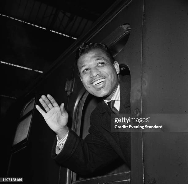 American boxer Sugar Ray Robinson smiling as he waves and leans out of the window a railway carriage, 20th November 1962.