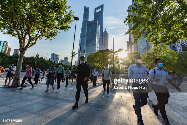 People with protective masks walk in street at Lujiazui on July 06, 2022 in Shanghai, China.