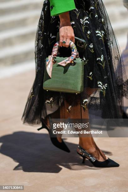 Guest wears a green buttoned jacket from Dior, a black tulle with embroidered white pearls and gold sequined flower pattern square-neck / midi dress,...