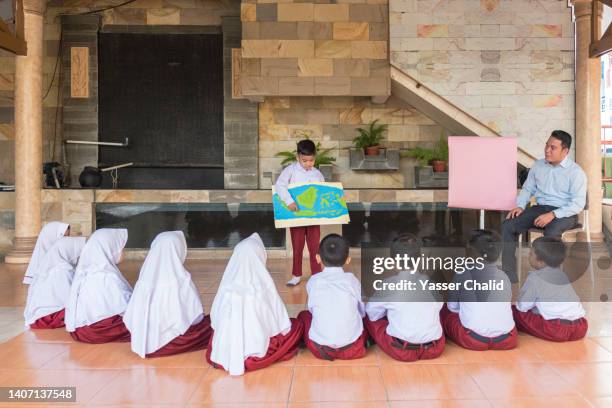 student showing the drawing of indonesian map  to classroom - indonesian girl stock pictures, royalty-free photos & images