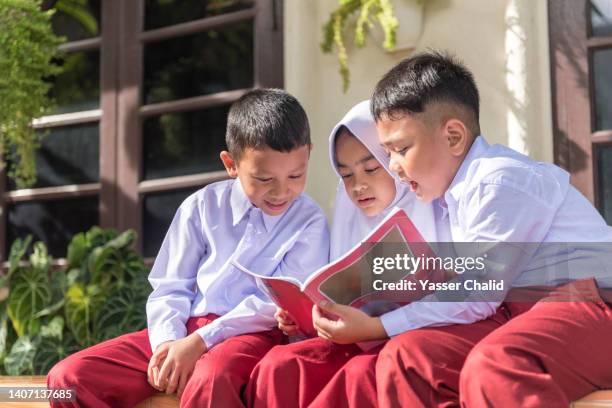 school children reading a text book - indonesian ethnicity stock pictures, royalty-free photos & images