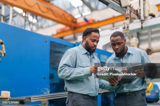 senior engineer explaining machine functioning to new engineer. - industrial worker tablet stock pictures, royalty-free photos & images