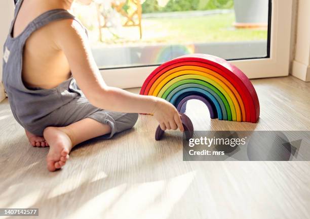little boy plays with a rainbow wooden toy - montessori education stock-fotos und bilder