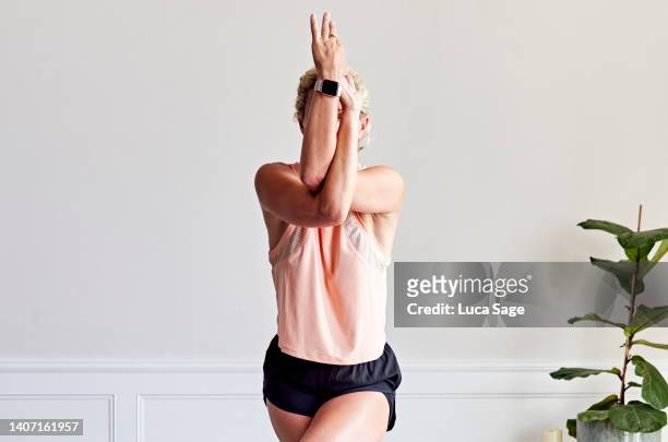 beautiful woman practising yoga in her living room - woman arm around stock pictures, royalty-free photos & images