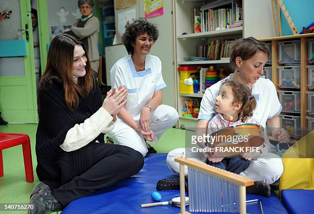 France's First Lady Carla Bruni-Sarkozy looks at a disabled child on March 5, 2012 during a visit at the Motor Reeducation Lapanouse-Debre center for...