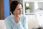 Young woman with severe toothache at home