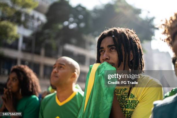brazilian fans watching a soccer match outdoors - a brazil supporter stockfoto's en -beelden