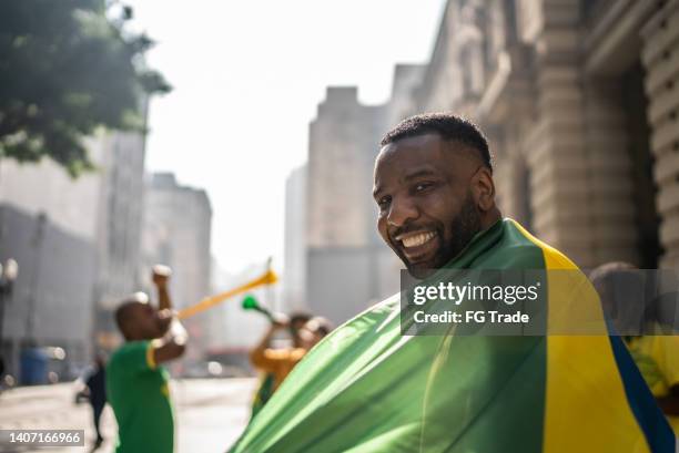 portrait d’un homme moyen avec le drapeau brésilien à l’extérieur - african soccer fans photos et images de collection