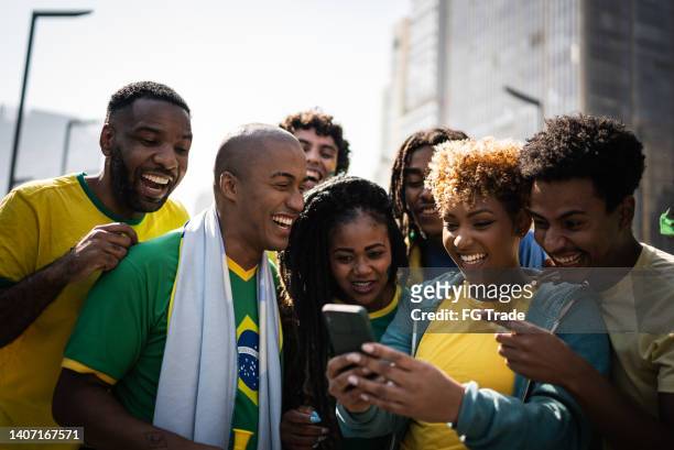 brazilian fans watching soccer game using mobile phone outdoors - international soccer event stock pictures, royalty-free photos & images