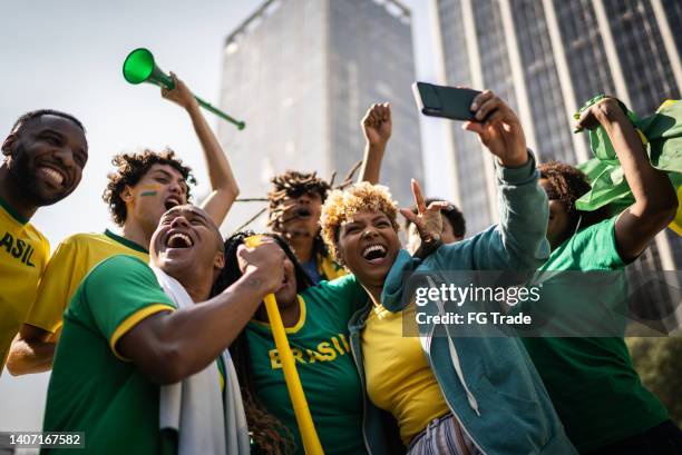 brazilian fans watching soccer game using mobile phone outdoors - brazil football imagens e fotografias de stock