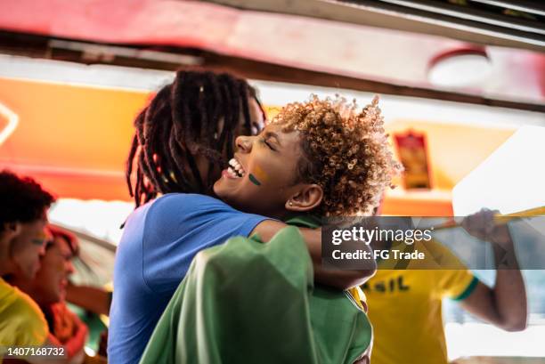 brazilian fans embraced celebrating a soccer game - internationaal voetbalevenement stockfoto's en -beelden