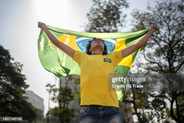 junger mann mit brasilianischer flagge im freien - brasilianische-flagge stock-fotos und bilder