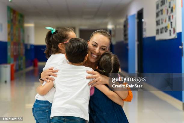 happy students embracing teacher in classroom - students-hugging-teacher stock pictures, royalty-free photos & images