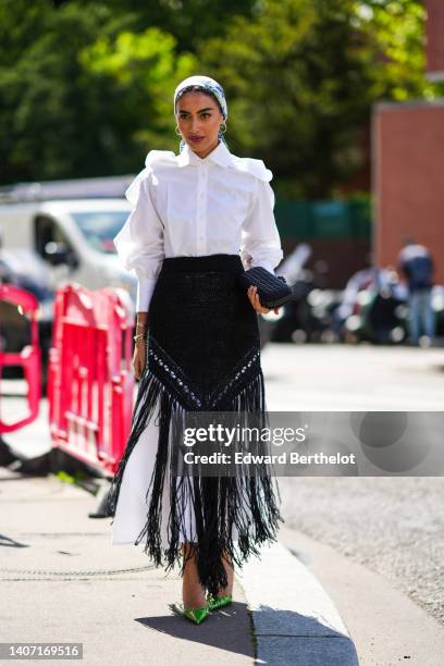 Guest wears a white with blue and beige print pattern silk scarf, silver earrings, a white puffy ruffled long sleeves shirt long dress, a black high...