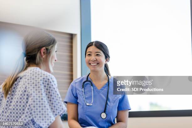 nurse smiles proudly to her patient - auscultation woman stock pictures, royalty-free photos & images