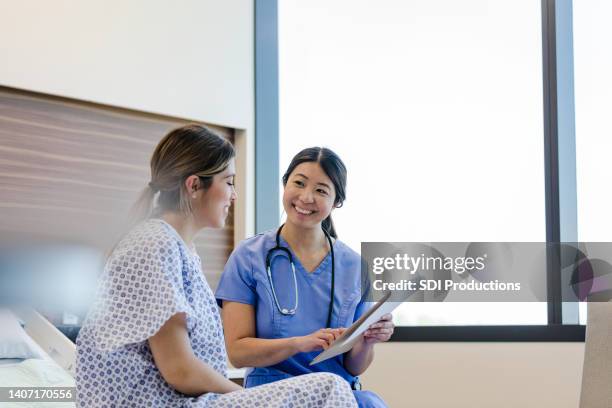 nurse smiles at her female patient - asian woman pregnant stockfoto's en -beelden