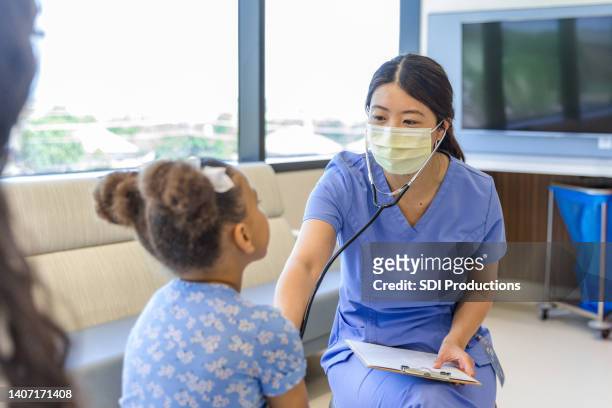 female doctor talks to girl while using stethoscope for examination - urgent care stock pictures, royalty-free photos & images