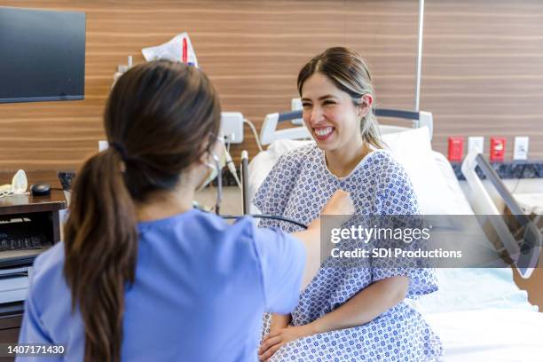 woman smiles during medical exam in hospital emergency room - bedside manner stock pictures, royalty-free photos & images